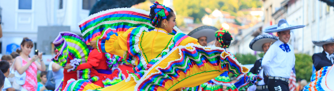 A woman in traditional Mexican dress dances in the streets during festivities