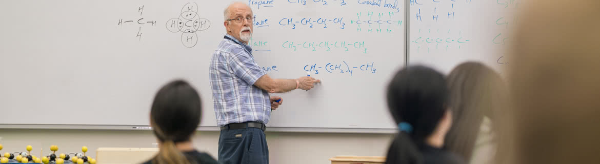 Professor explains chemistry formulas on whiteboard