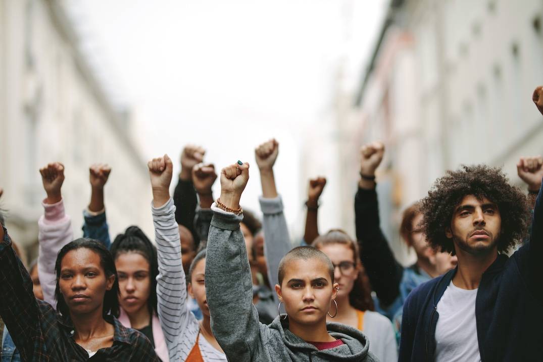 Image of young protestors holding up fists and staring ahead.